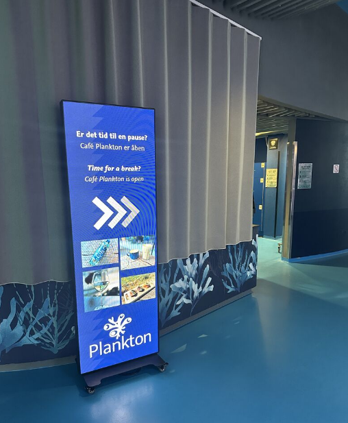 LED poster på Den Blå Planet med vejvisning og information om Café Plankton